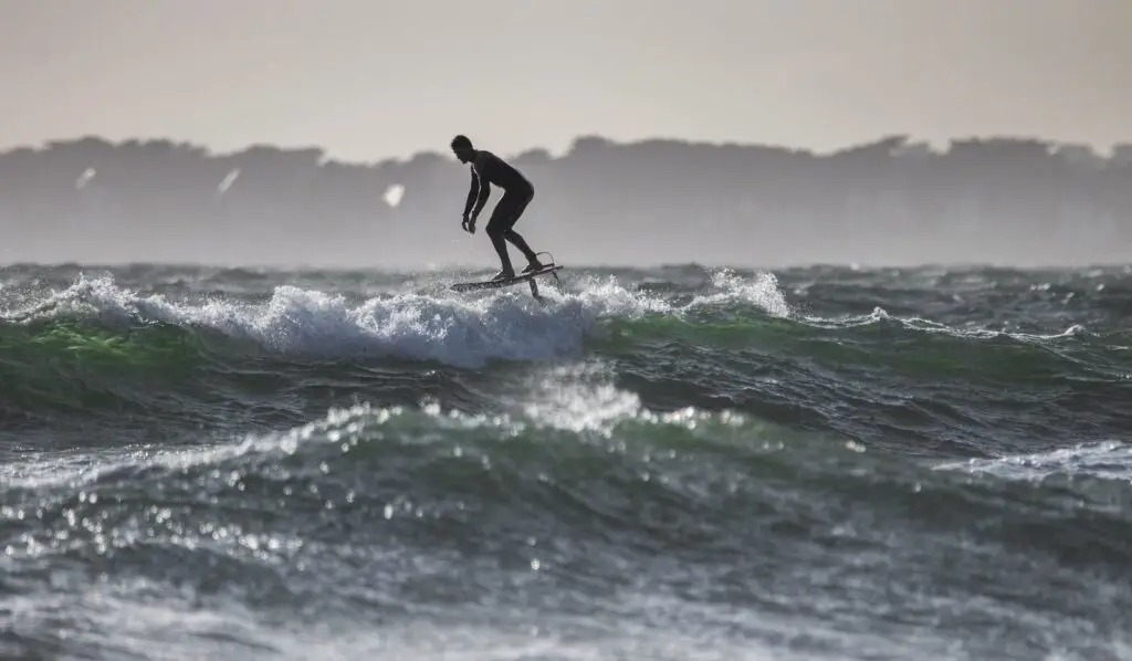 time lapse photography of man riding a foil (hydrofoil) surfboard