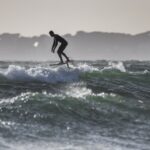 time lapse photography of man riding a foil (hydrofoil) surfboard